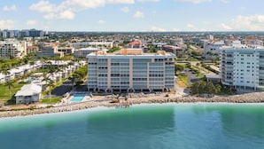 Un hotel sulla costa con piscina, vista sulla spiaggia e diversi edifici sullo sfondo.