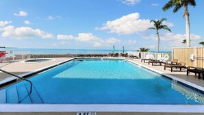 Una piscina con indicatore di profondità di 3 piedi, circondata da sdraio e palme, con vista sull'oceano.