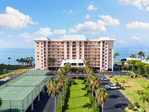 Een meerlaags hotel met een tennisbaan en een parkeerplaats.