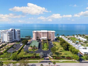 Hotel com vários edifícios, quadra de tênis e estacionamento.