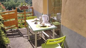 Una pequeña mesa al aire libre con sillas, un letrero y vistas a un área boscosa.