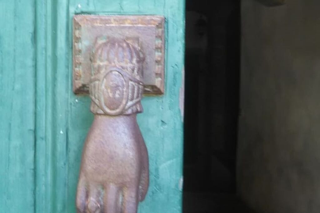 A rustic door with a metal handle and a decorative figure.