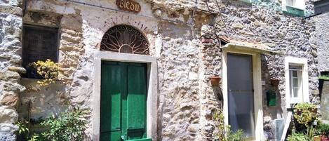 A stone building with a green door and a sign that reads "Biedu".