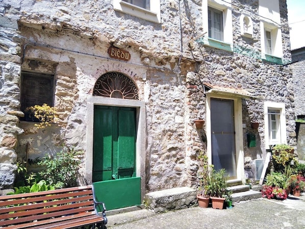 A stone building with a green door and a sign that reads "Biedu".
