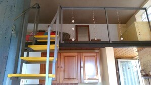 Un espacio tipo loft con entrepiso, armarios de madera y una escalera.