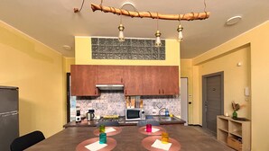 Una cocina moderna con comedor, que incluye una mesa de madera, sillas negras y una lámpara colgante.
