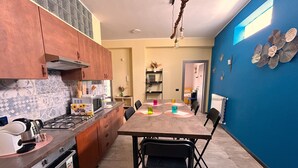 Una cocina con mesa de comedor, sillas y una pared azul destacada.