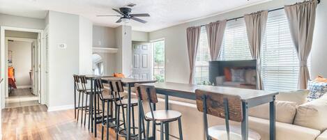 A modern kitchen with a bar area, wooden flooring, and a ceiling fan.