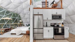 A compact, modern interior with a kitchenette, a bed, and a dining area, all within a geodesic dome structure. - Dream Dome - Romantic Retreat + Wifi A/C + Hot Tub (Luray)