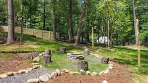 A forested campsite with a fire pit surrounded by rocks and trees. - Dream Dome - Romantic Retreat + Wifi A/C + Hot Tub (Luray)