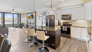 Una cocina moderna con una isla central, armarios blancos y electrodomésticos de acero inoxidable.