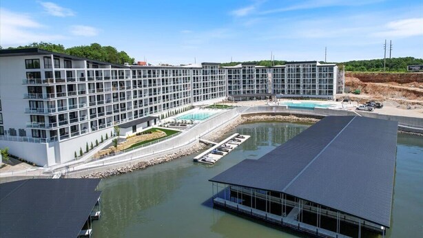Un hotel moderno con una piscina grande, un área exterior cubierta y vistas al agua.