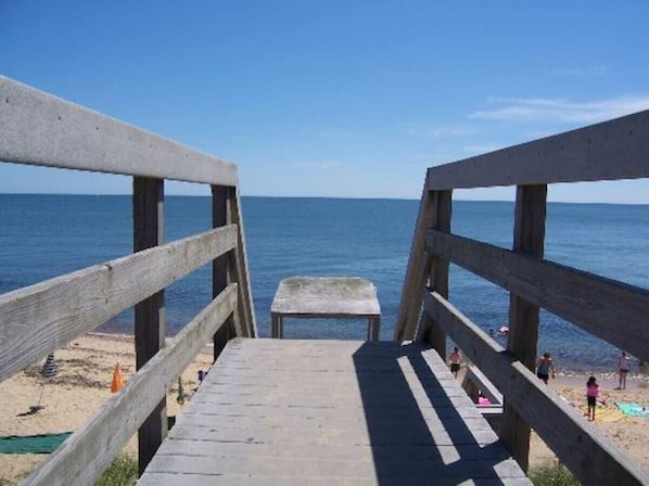 A wooden boardwalk leading to a beach with a clear view of the ocean.