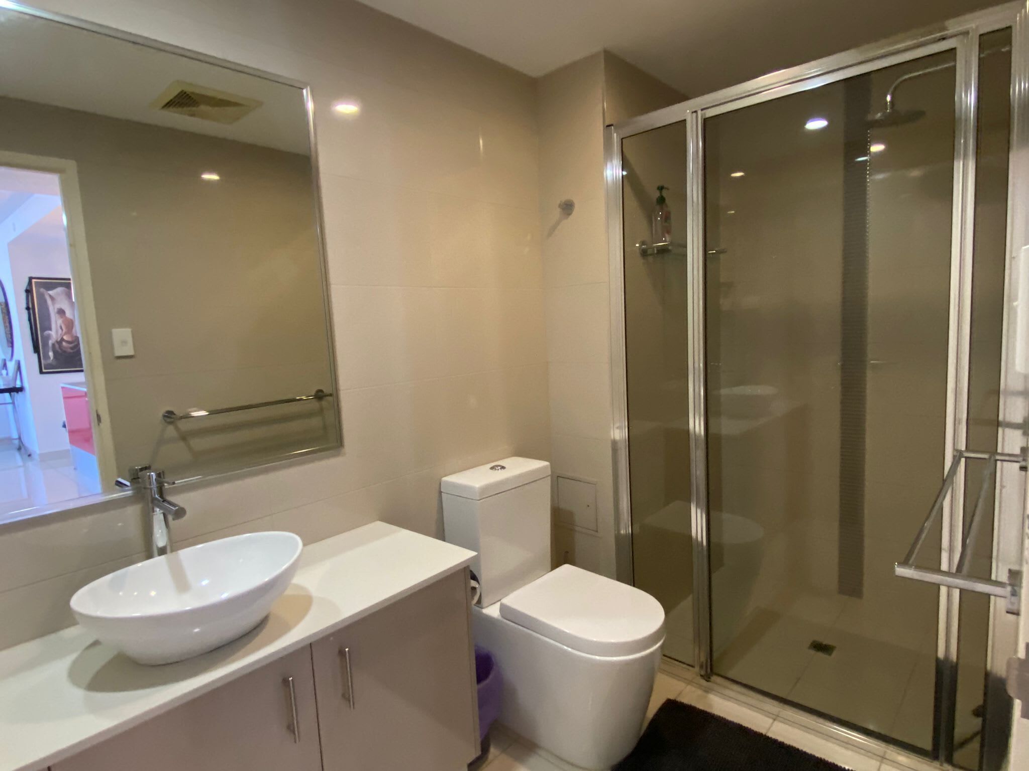 A modern bathroom with a white sink, toilet, and glass shower enclosure.