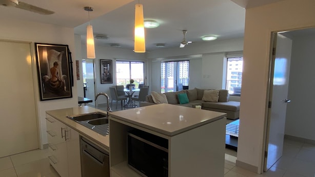 A modern kitchen with a central island, a dining area with a table and chairs, and a living area with a sofa and a television. - Katara on Smith (Darwin)