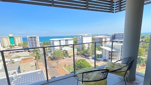 A balcony with two chairs and a view of the city and ocean. - Katara on Smith (Darwin)