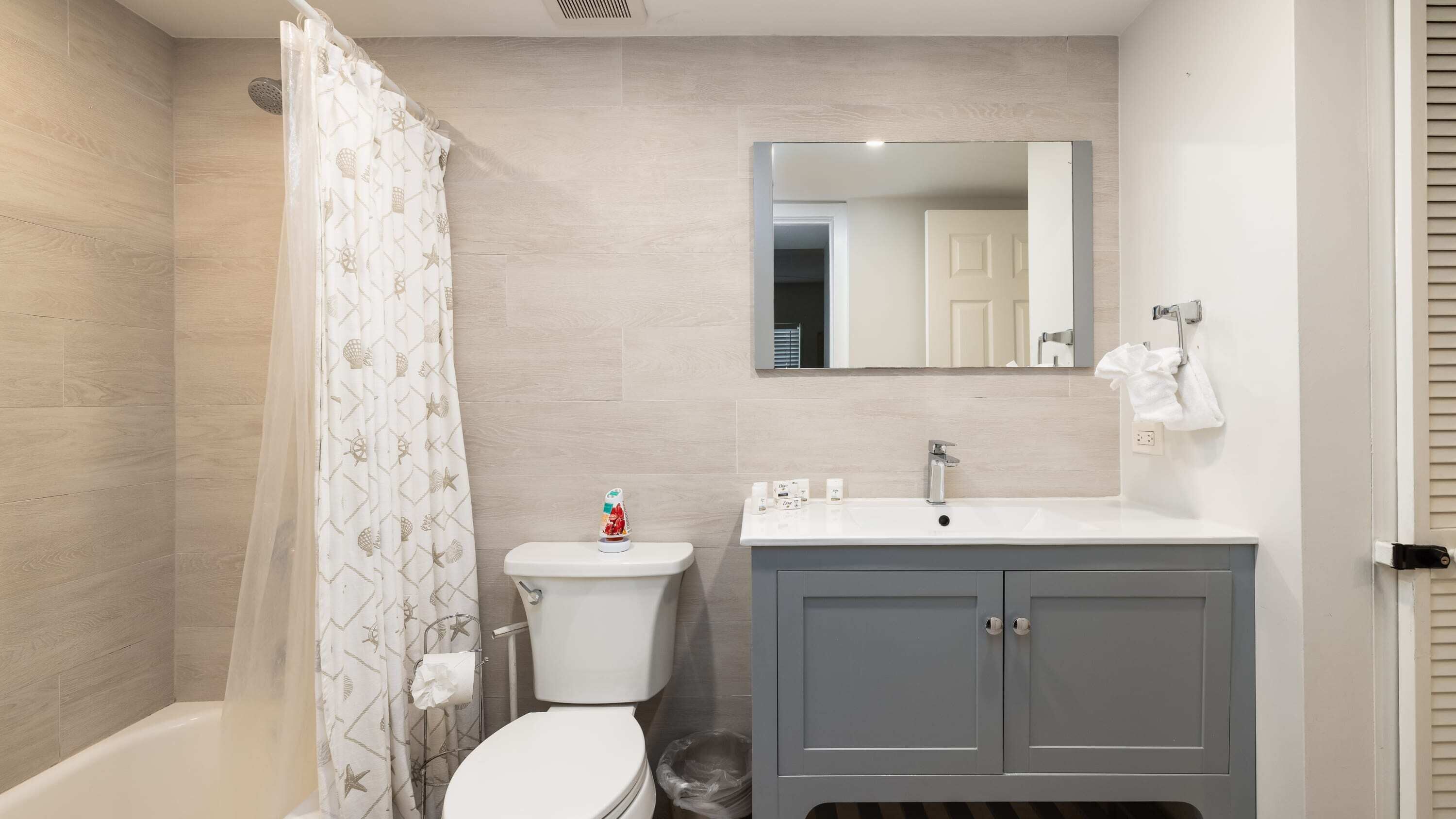 Une salle de bain équipée d’une douche, de toilettes, d’un lavabo et d’un meuble de rangement.