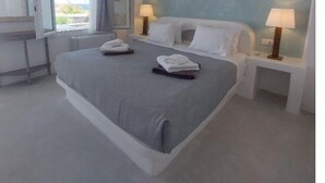 Camera d'albergo moderna con un grande letto, due comodini con lampade, una finestra con tende e vista sull'esterno.