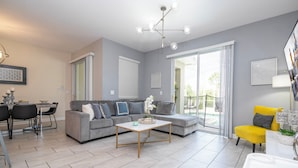 A modern living room with a grey sofa, a yellow armchair, a coffee table, and a dining area with a table and chairs. - Modern 4Bed+PrivatePool Resort Style 8959 (Davenport)