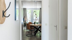 En hall som leder till en matplats med trägolv, en vit dörr och ett matbord med stolar.