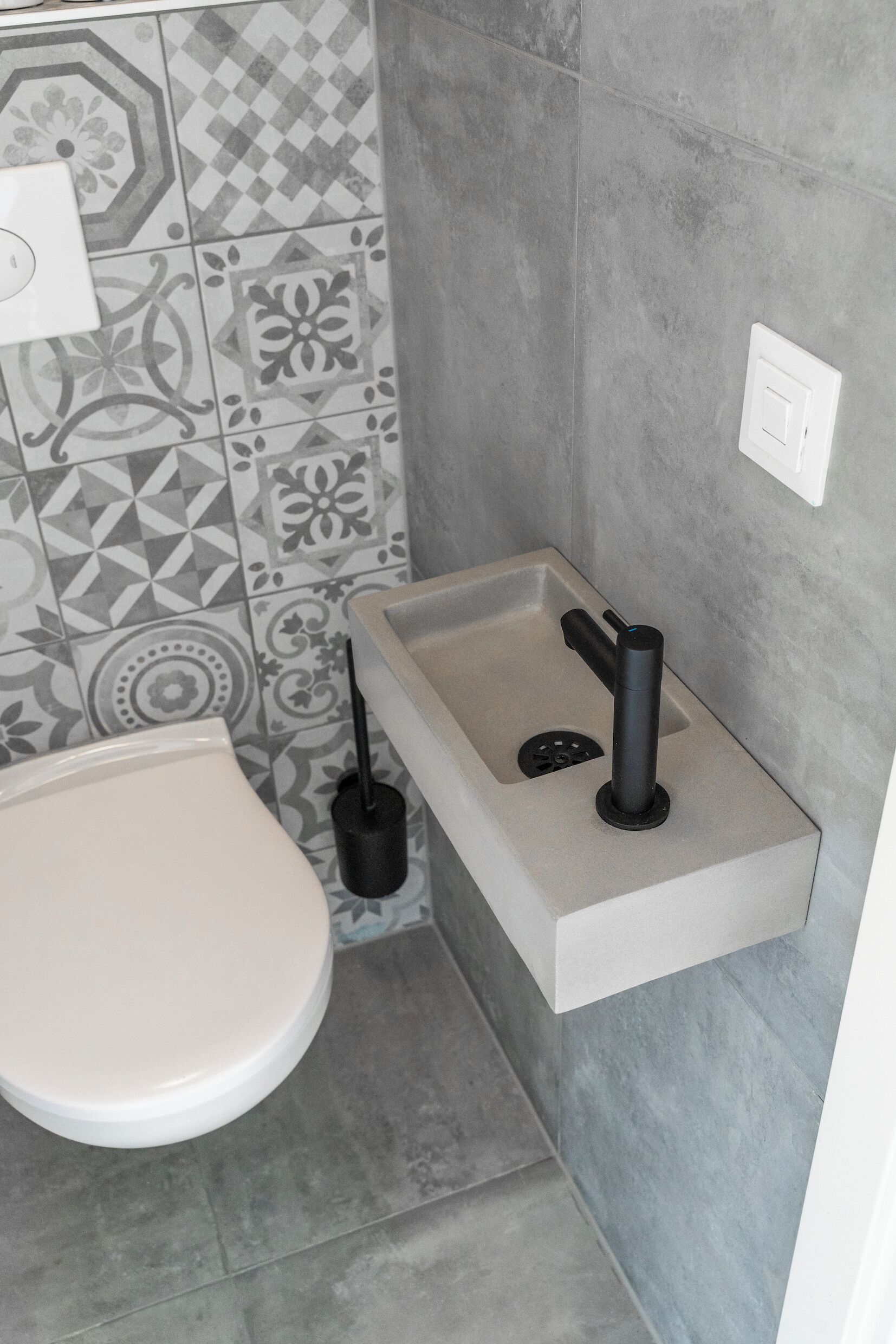 Une salle de bain comprenant des toilettes, un lavabo avec un robinet et une brosse pour les toilettes.
