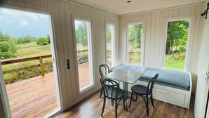 Una habitación con terraza de madera, una mesa con dos sillas y un banco con cojín.
