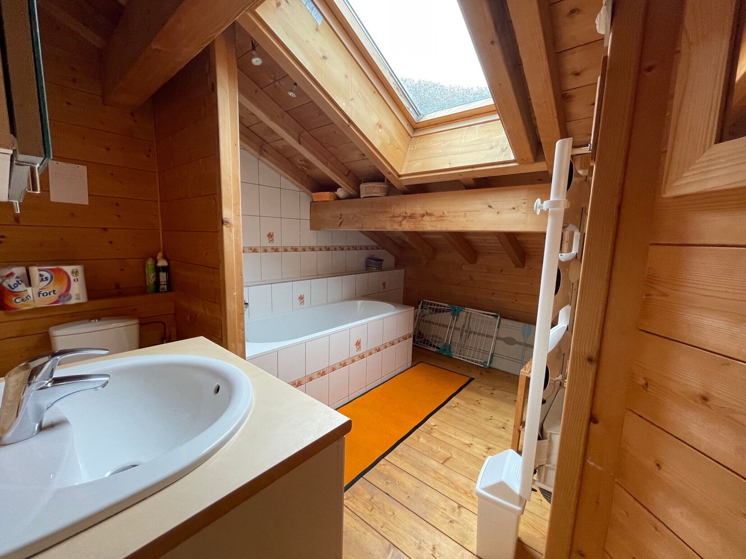 A wooden cabin with a skylight, a sink, a bathtub, and a toilet.