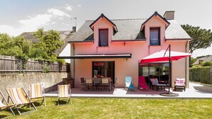 Een huis met twee verdiepingen, een overdekte patio, terras en een omheinde achtertuin.