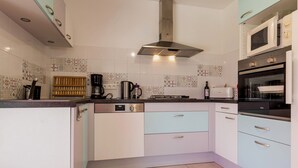 Een moderne keuken met witte kasten, een roestvrijstalen afzuigkap, een koffiezetapparaat en een magnetron.