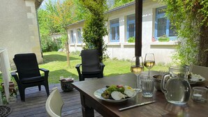 An outdoor dining area with a wooden table set for two, surrounded by chairs.