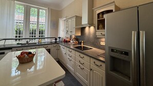 A modern kitchen with white cabinets, a stainless steel refrigerator, and a large window providing natural light.