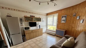 Un espacio habitable compacto con kitchenette, un sofá marrón y una ventana con vistas.