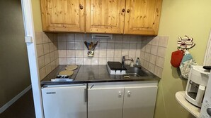 A compact kitchen with wooden cabinets, a refrigerator, a sink, and a microwave. - Cozy T2 in Station Center, Near Shops and Slopes (Le Lioran)
