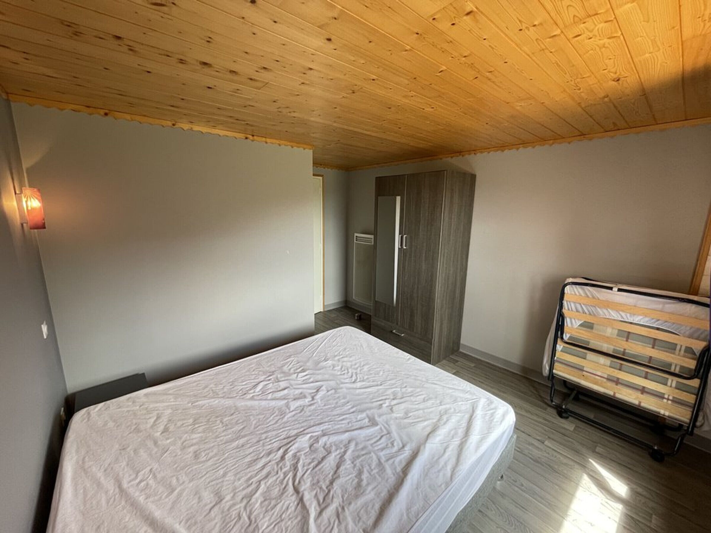 Een slaapkamer met een bed, een kledingkast en een bed op wielen.