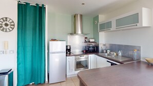 A compact kitchen with a refrigerator, microwave, coffee maker, and a sink. - Quiet Apartment with Terrace, Parking, and AC, 5 Min Drive to Beach (Frontignan)
