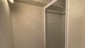 A bathroom with a shower, a wooden bench, and a tiled wall.