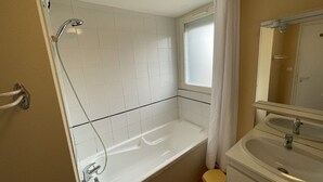 A bathroom with a bathtub, a sink, and a window.