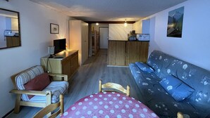 A compact living space with a sofa, a dining table, and a kitchenette area.