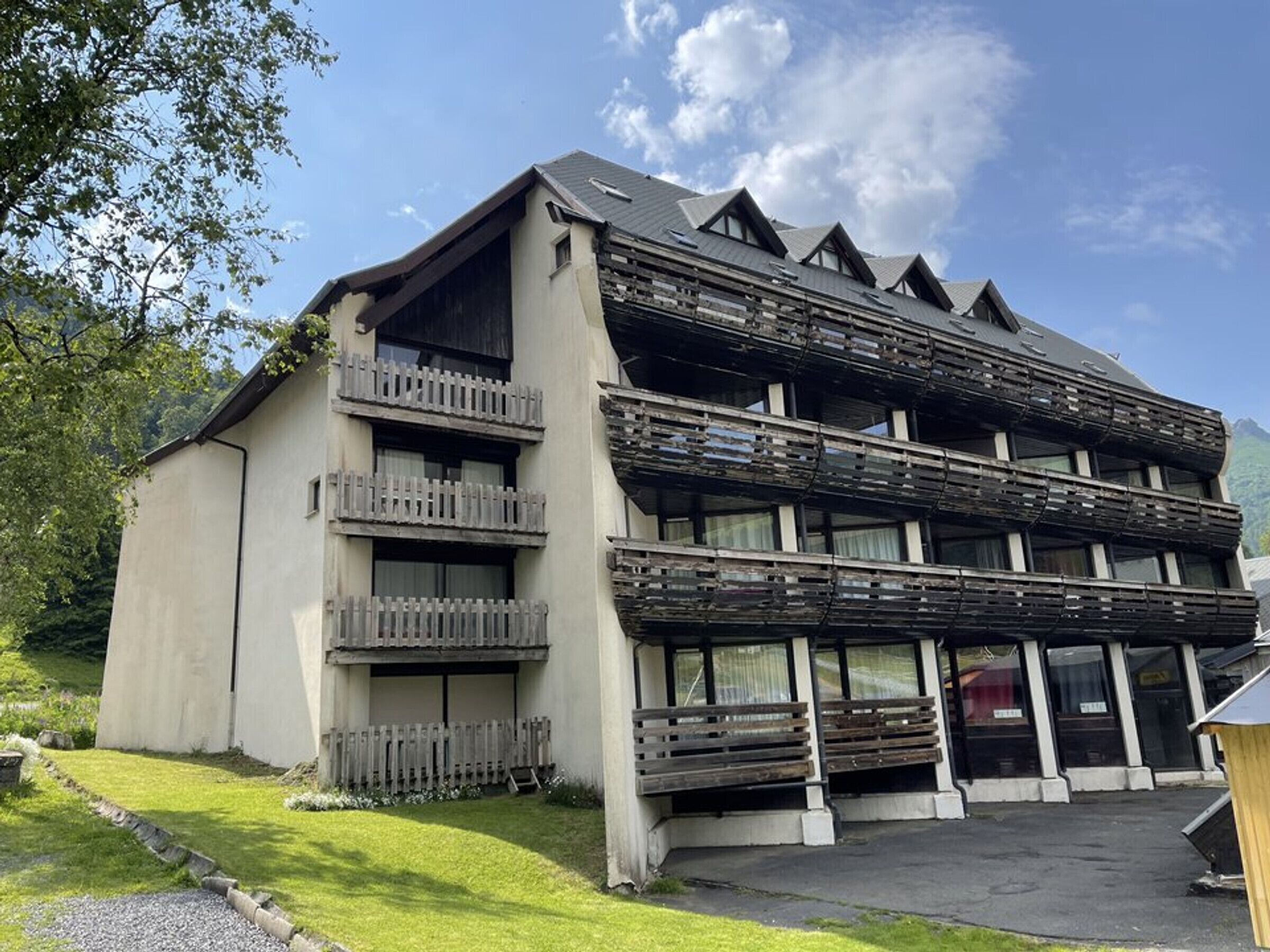 Un immeuble à plusieurs étages doté de balcons, d’un toit plat et d’une allée pavée.