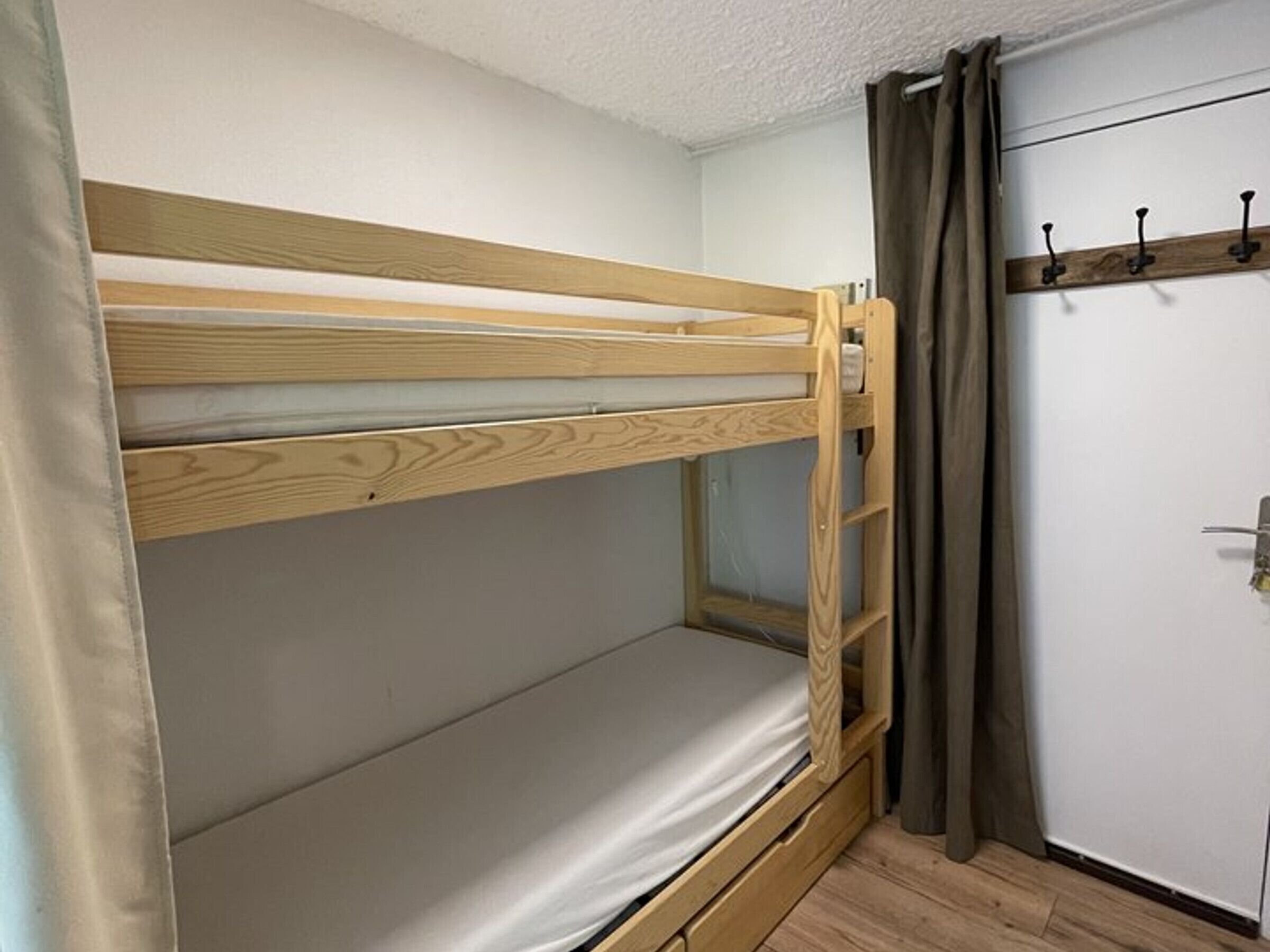 Un lit superposé avec une structure en bois et un matelas simple.