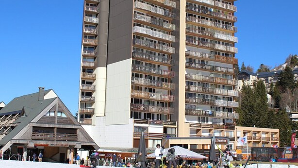 A multi-story hotel with balconies, ski equipment, and a ski slope in the foreground. - Ski-in/Ski-out Studio with Balcony and WiFi in Laveissière (Le Lioran)