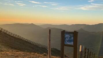 A mountainous landscape with a wooden fence and a signpost.