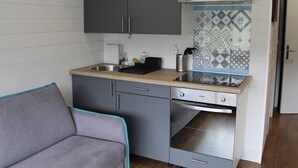 A compact kitchen with grey cabinets, a stainless steel sink, and a built-in oven. - Ski-in/Ski-out Studio with Balcony and WiFi in Laveissière (Le Lioran)