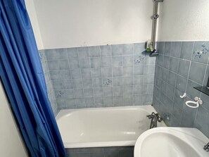 A bathroom with a bathtub, a shower, and a sink. - Cozy Studio with South-Facing Terrace, Close to Amenities, Ski Lifts, and Skating Rink (Le Lioran)