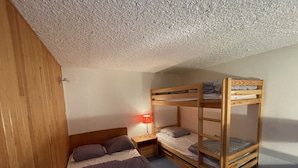 A bunk bed room with a single bed and a nightstand with a lamp. - Central Duplex with Balcony – Sleeps 6/8, Pets Welcome (Le Lioran)