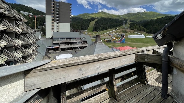 A view from a wooden balcony overlooking a mountainous area with a large building and a ski lift. - Central Duplex with Balcony – Sleeps 6/8, Pets Welcome (Le Lioran)
