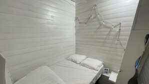 A small, single-bed room with white bedding and a simple, clean design. - Central studio with balcony and WiFi (Le Lioran)