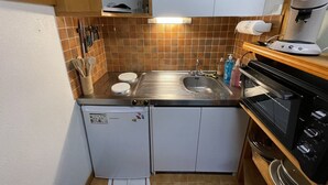 A compact kitchen with a sink, stove, and a small refrigerator.