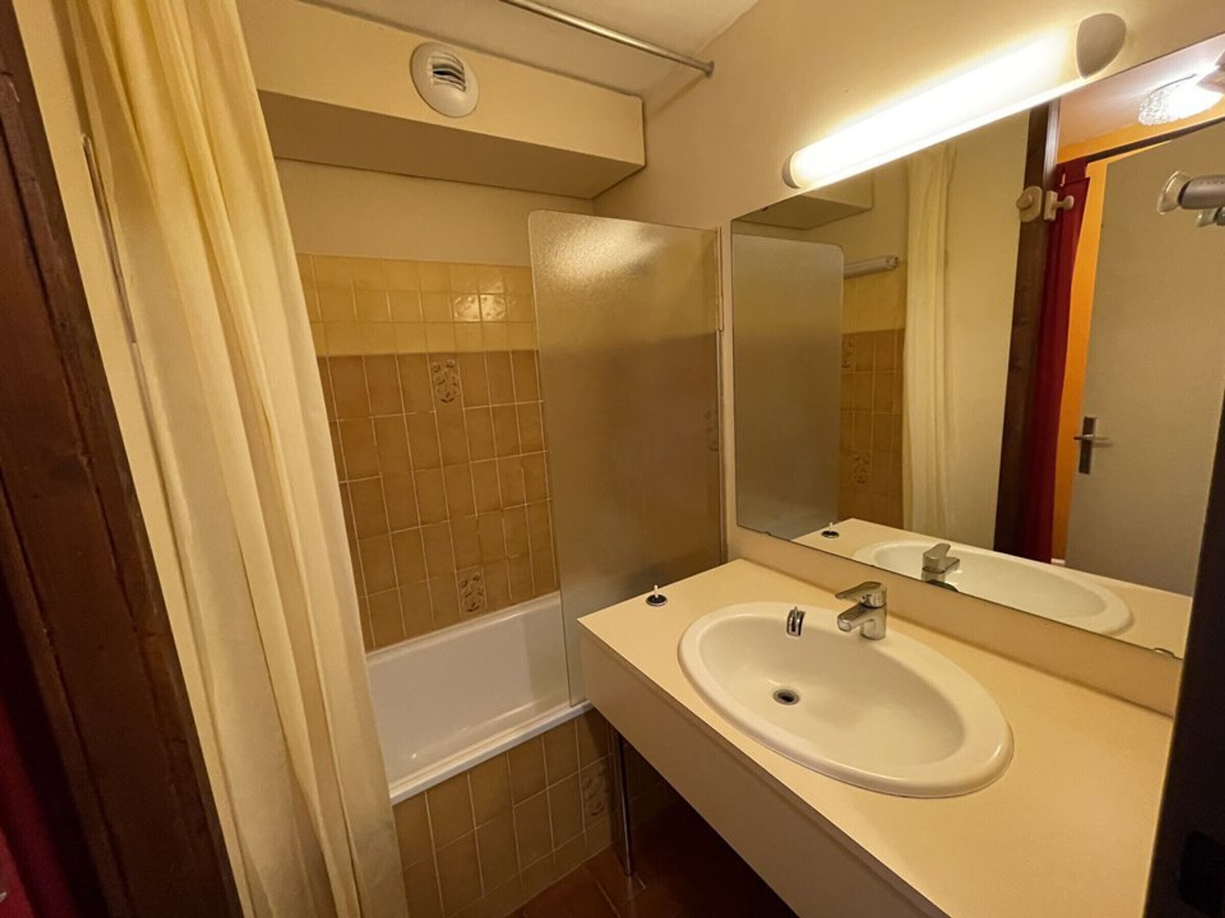 A bathroom with a bathtub, a sink, and a mirror.