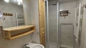 A bathroom with a sink, mirror, wooden cabinet, and a shower enclosure. - Cozy South-Facing Studio with Mezzanine, Near Slopes, Ski Shuttle, & Free Parking (Le Lioran)